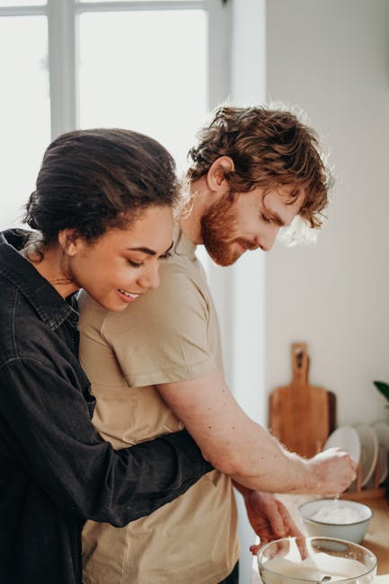 A joyful couple embraces while preparing breakfast in their cozy kitchen.